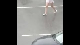 Dancing in the rain with wet white shirt on a busy parking loot