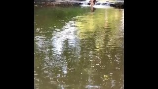 Girl exposes breasts under the waterfall